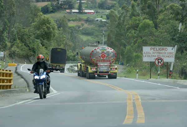 Carretera en donde se observan una moto, un camión y un camión cisterna