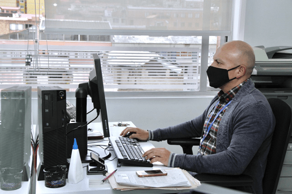 Hombre con tapabocas trabajando en un computador