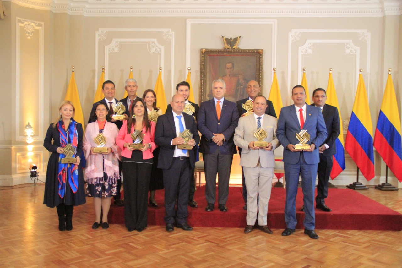 Personas posando frente a un foto con el galardón del Premio Nacional de Alta Gerencia 