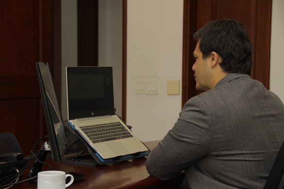 Hombre frente a un computador y de espaldas. 