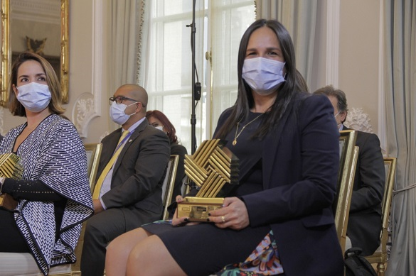 Se observa en primer plano una mujer con tapabocas sosteniendo el trofeo del Premio Nacional de Alta Gerencia