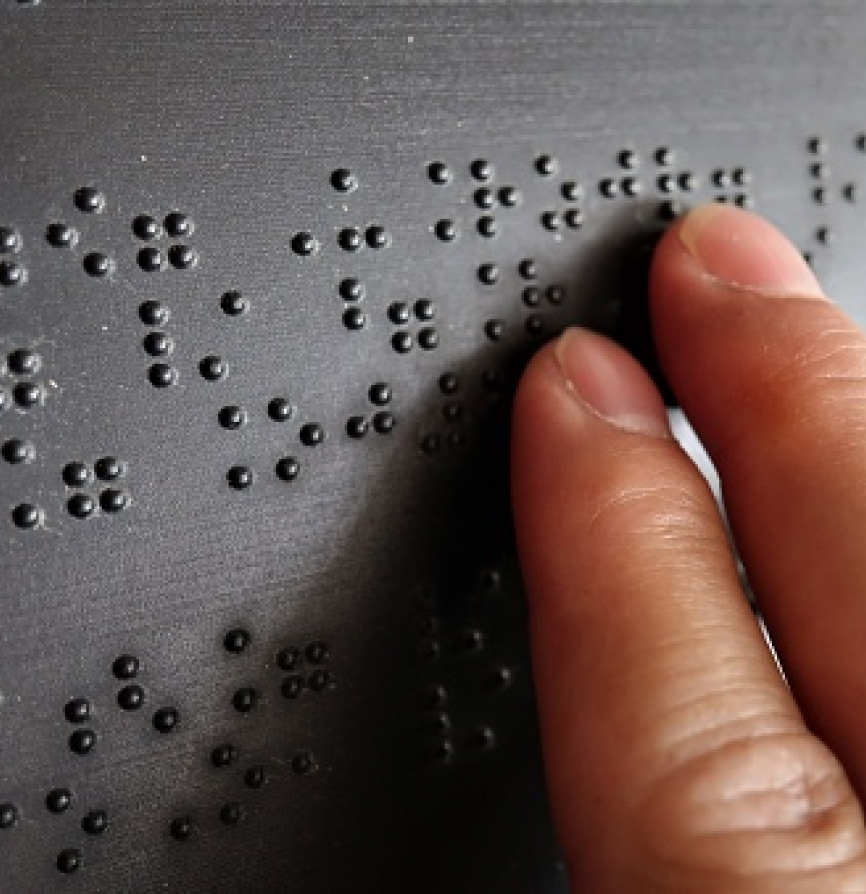 Una persona realizando una lectura sobre una frase en braille